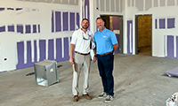  Two men standing side by side in a school building under construction.